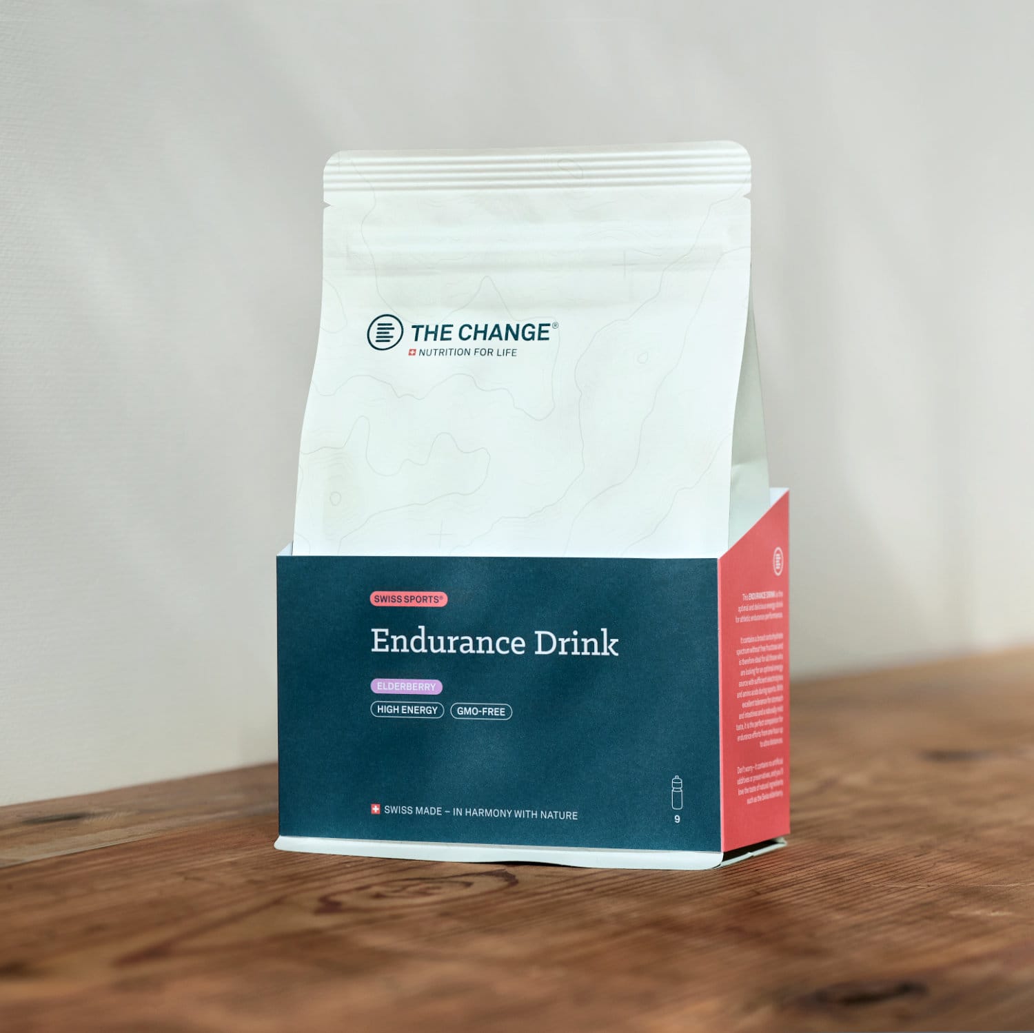 White and red pouch of "Endurance Drink" with high-energy, vegan formula, on a wooden surface. Swiss-made.