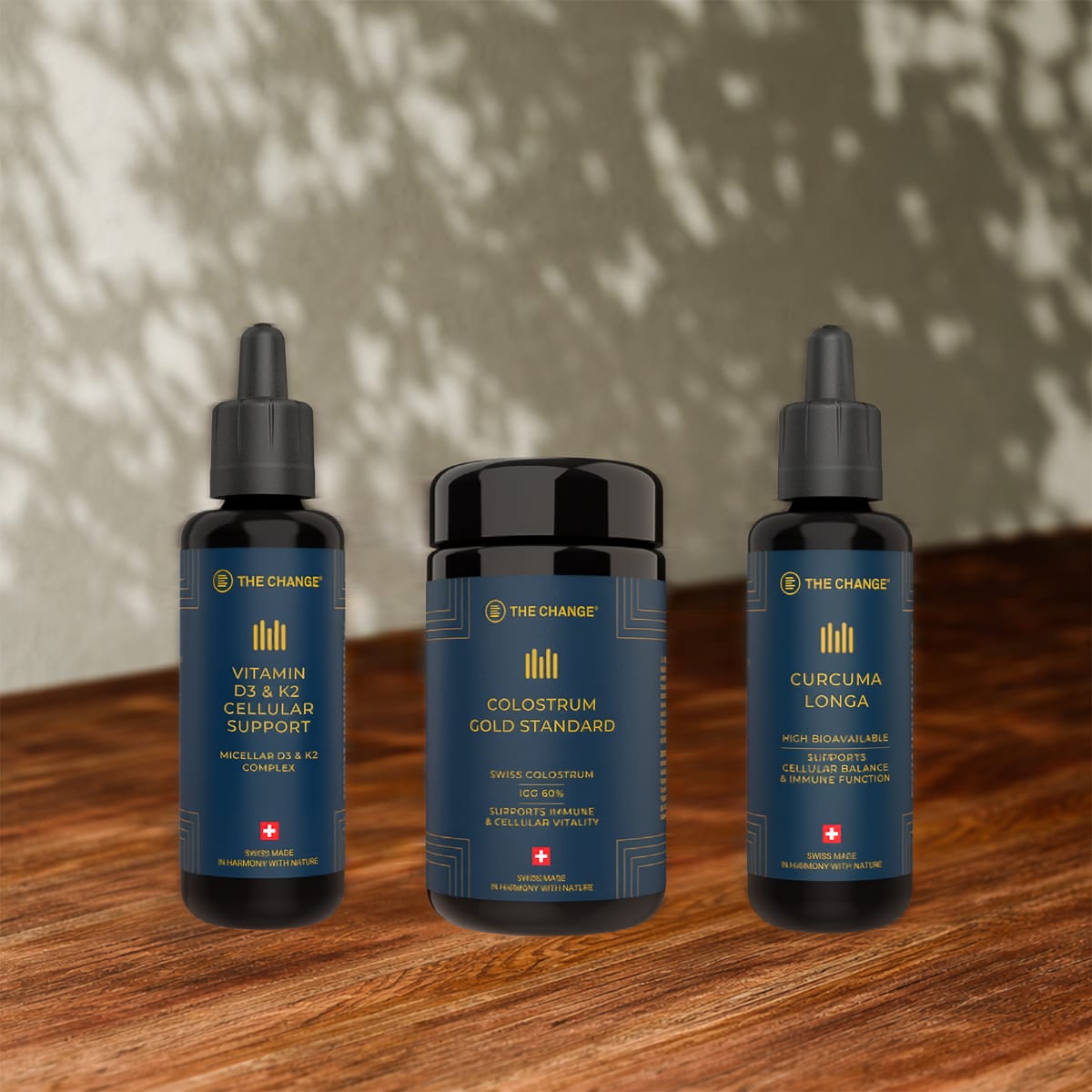 trio of health supplements featuring Vitamin D3 & K2, Colostrum Cold Standard, and Curcuma Longa in elegant black bottles.