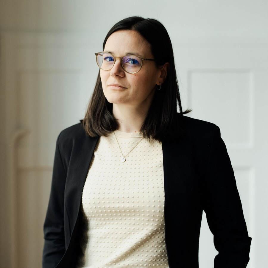 Smart casual women's outfit: black blazer, cream textured top, and sleek glasses, perfect for professional settings.
