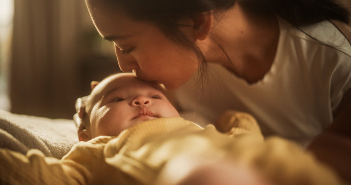 Mutter küsst ihr Baby auf die Stirn