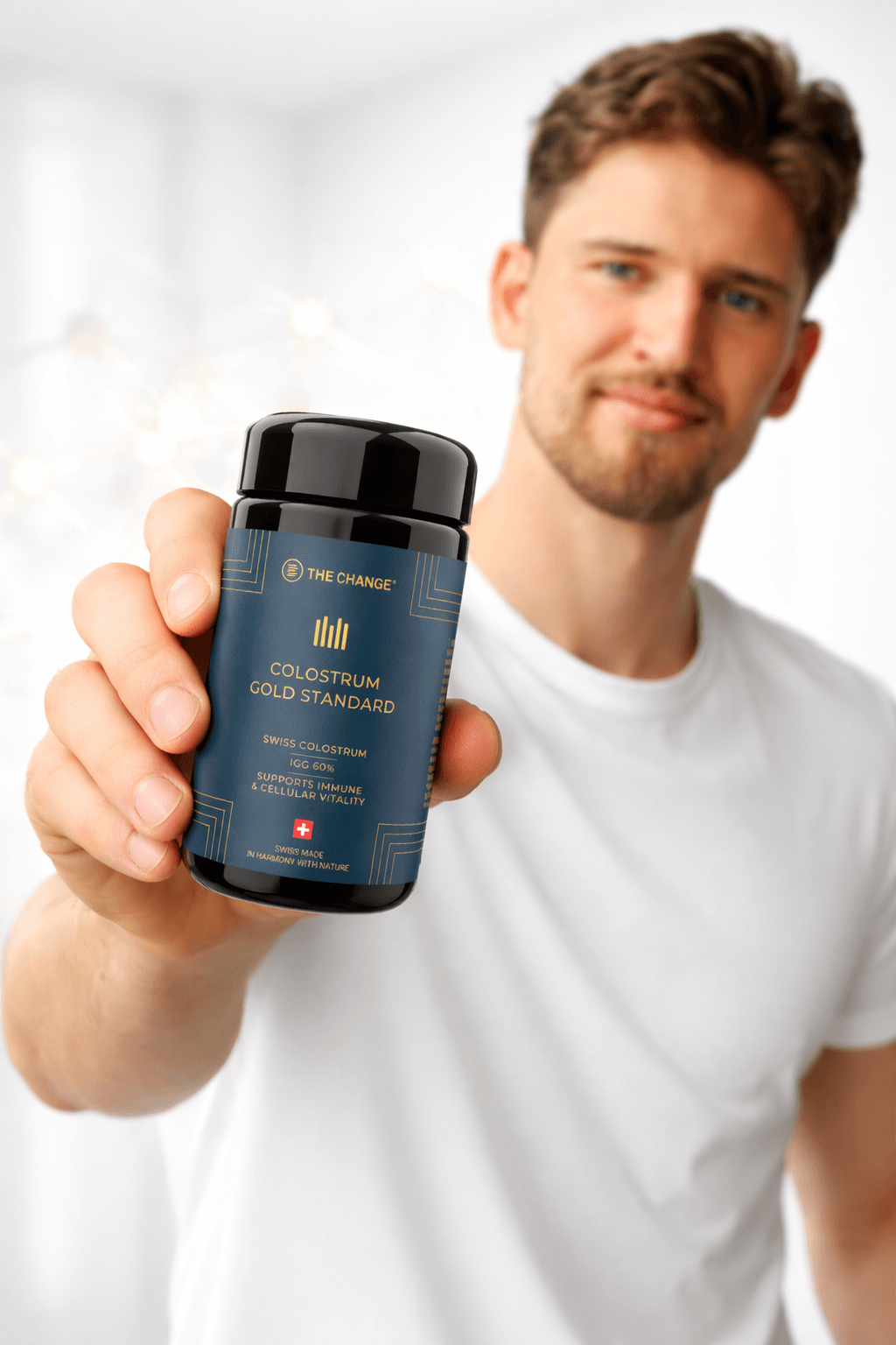 Black and gold colostrum supplement bottle held by a man in a white shirt, modern design, Swiss-made quality.