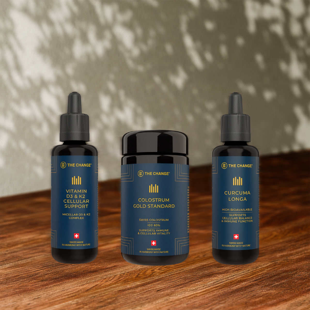 trio of health supplements featuring Vitamin D3 & K2, Colostrum Cold Standard, and Curcuma Longa in elegant black bottles.